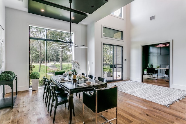 dining space featuring hardwood / wood-style floors, a high ceiling, and a notable chandelier