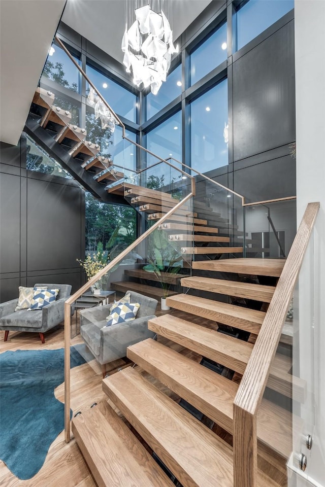 staircase featuring a high ceiling, hardwood / wood-style flooring, and expansive windows