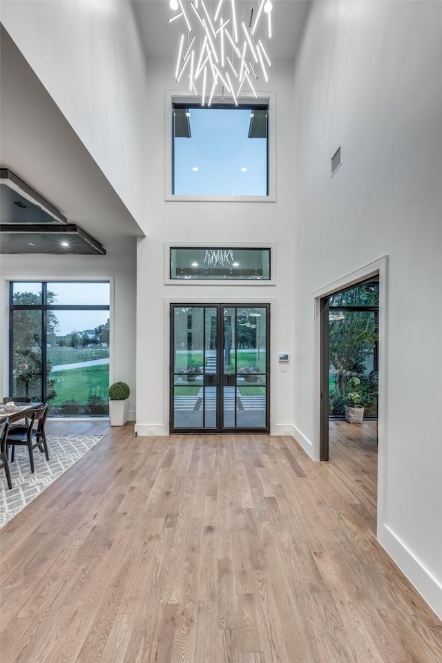 unfurnished living room featuring a towering ceiling and light wood-type flooring