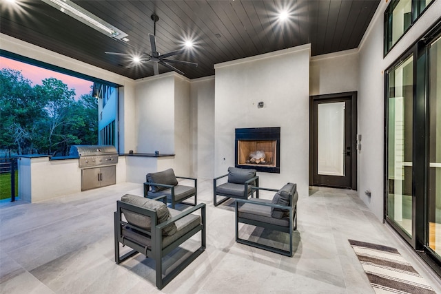 patio terrace at dusk featuring an outdoor living space with a fireplace, ceiling fan, exterior kitchen, and a grill