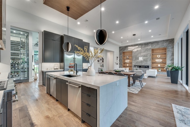 kitchen with sink, a spacious island, decorative light fixtures, and light hardwood / wood-style floors