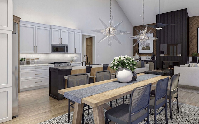 dining area featuring light hardwood / wood-style floors, high vaulted ceiling, and ceiling fan