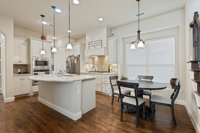 kitchen featuring a center island, white cabinetry, stainless steel appliances, pendant lighting, and dark wood-type flooring