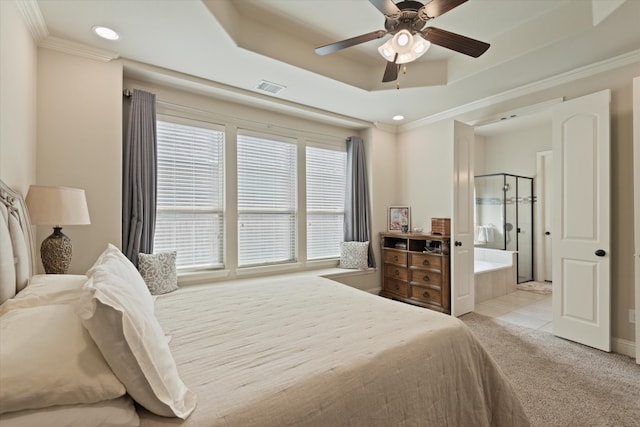 bedroom with light carpet, ceiling fan, a tray ceiling, ensuite bathroom, and crown molding