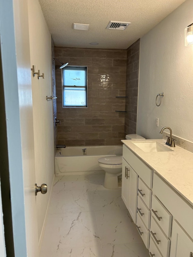 full bathroom with vanity, tiled shower / bath combo, a textured ceiling, and toilet