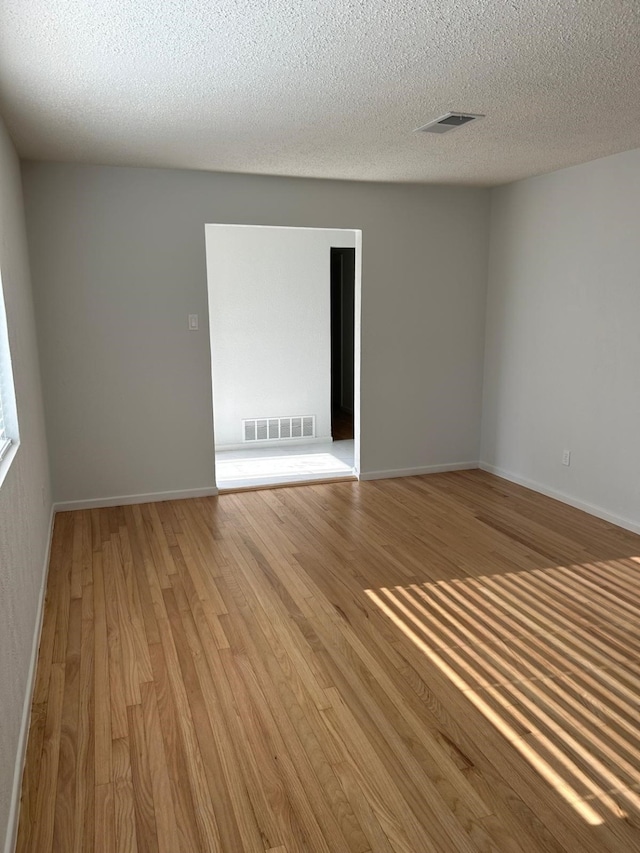 spare room with a textured ceiling and light wood-type flooring