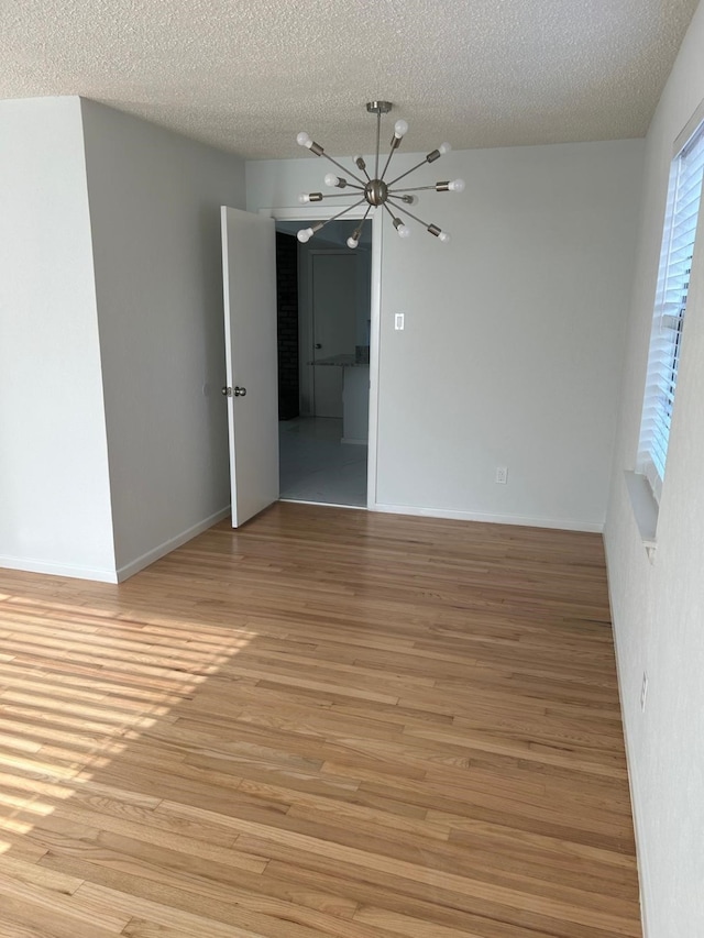 empty room with light hardwood / wood-style floors and a textured ceiling