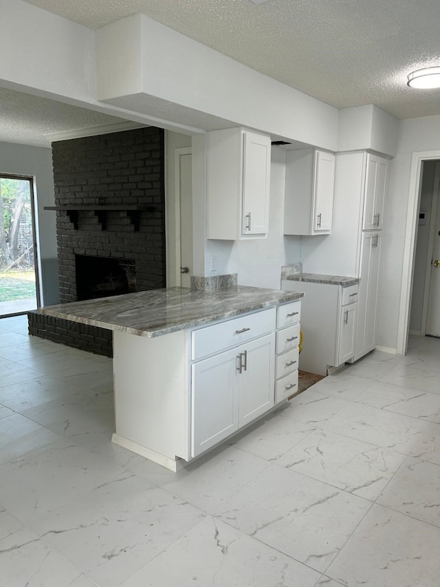 kitchen with kitchen peninsula, white cabinets, a textured ceiling, and a breakfast bar area