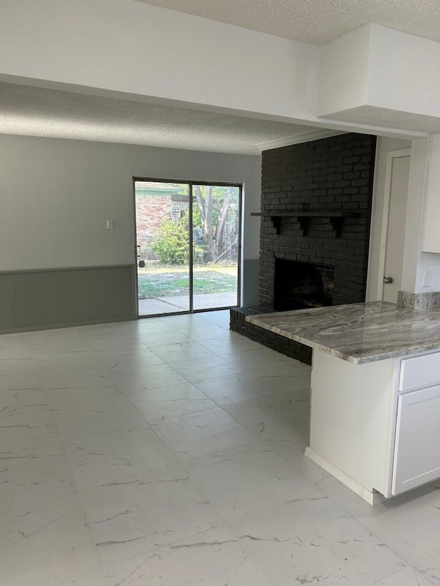 unfurnished living room with a textured ceiling and a brick fireplace