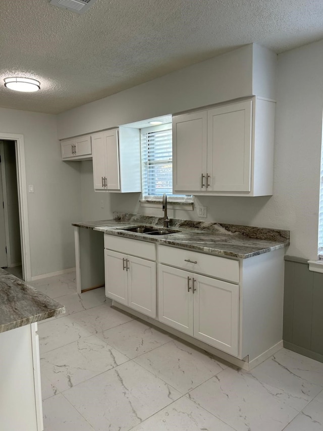 kitchen featuring white cabinetry, a textured ceiling, and sink