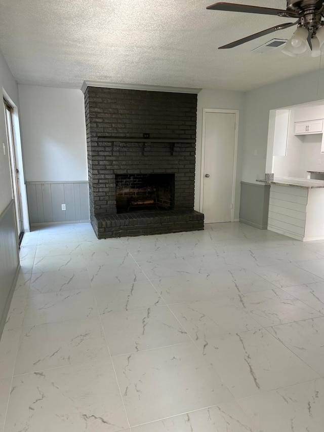 unfurnished living room with a brick fireplace, a textured ceiling, and ceiling fan