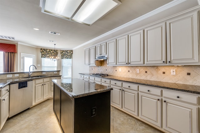 kitchen with ornamental molding, sink, a center island, and dark stone countertops