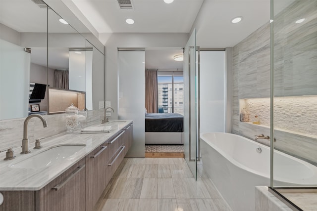 ensuite bathroom with double vanity, a freestanding bath, a sink, and ensuite bathroom