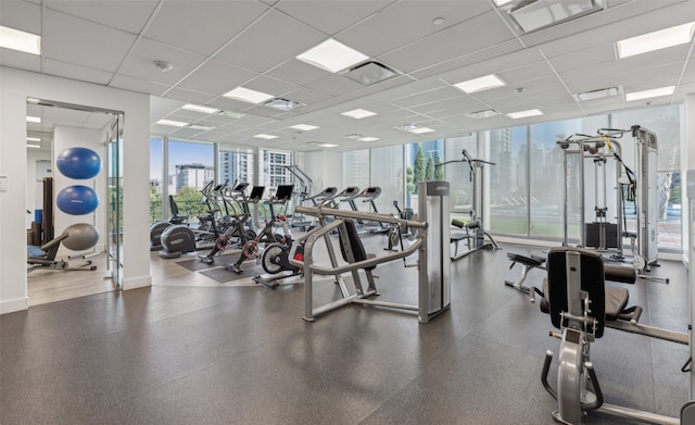 exercise room with a wall of windows, visible vents, a city view, and a paneled ceiling