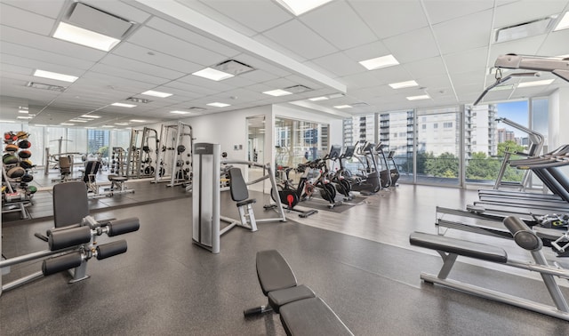 workout area with a wall of windows, a city view, a paneled ceiling, and visible vents