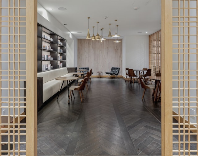 dining area with dark parquet floors and wood walls