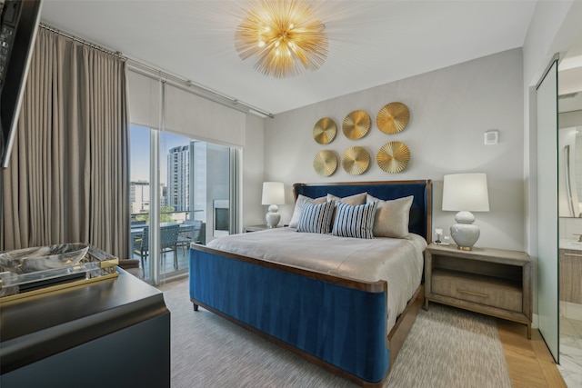 bedroom featuring hardwood / wood-style floors, access to outside, and a chandelier