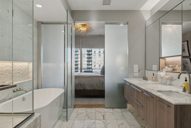 ensuite bathroom with a sink, a freestanding tub, visible vents, and marble finish floor