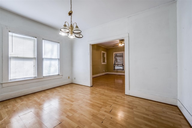 unfurnished dining area featuring ornamental molding, ceiling fan with notable chandelier, and light hardwood / wood-style floors