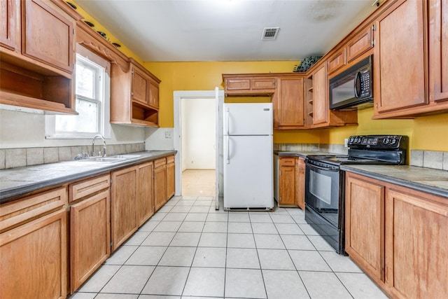 kitchen featuring light tile patterned floors, black appliances, and sink