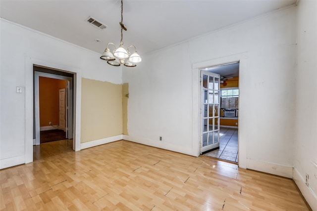 unfurnished dining area featuring ornamental molding, a chandelier, and hardwood / wood-style floors