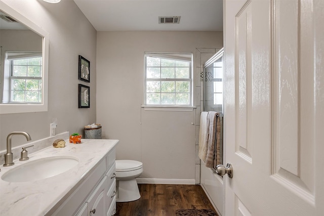 bathroom with vanity, toilet, hardwood / wood-style flooring, and walk in shower