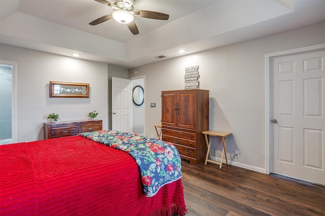 bedroom featuring dark hardwood / wood-style flooring, a raised ceiling, and ceiling fan