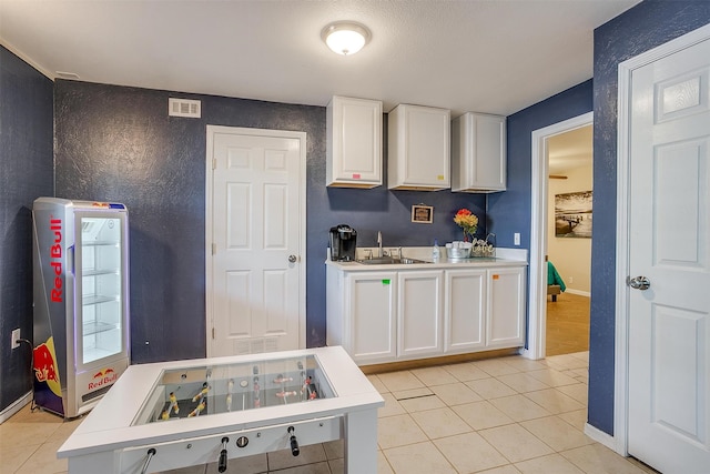 kitchen with white cabinetry, sink, and light tile patterned floors