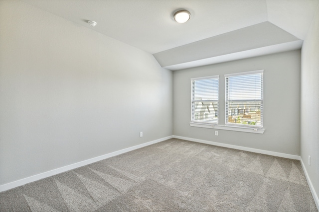 carpeted empty room featuring lofted ceiling