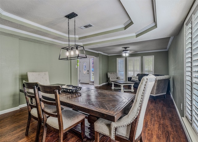 dining room with ornamental molding, ceiling fan with notable chandelier, dark hardwood / wood-style floors, and a raised ceiling