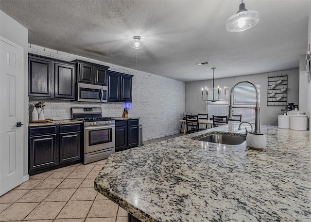 kitchen with sink, pendant lighting, appliances with stainless steel finishes, and an inviting chandelier