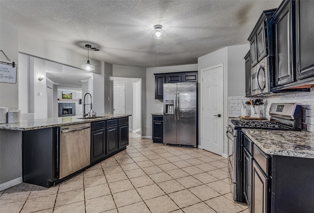 kitchen with stainless steel appliances, sink, a textured ceiling, light tile patterned floors, and decorative backsplash