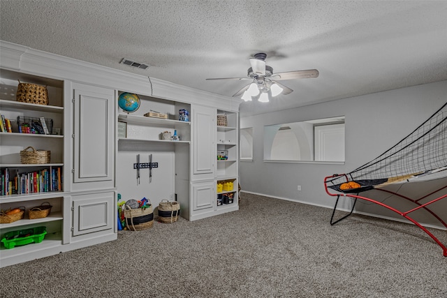 playroom with a textured ceiling, carpet flooring, and ceiling fan