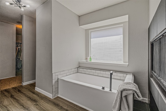 bathroom featuring a textured ceiling, a bathing tub, and hardwood / wood-style flooring