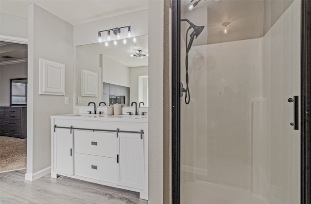 bathroom with hardwood / wood-style floors, vanity, and a shower