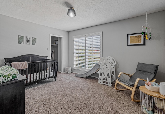 carpeted bedroom with a nursery area and a textured ceiling