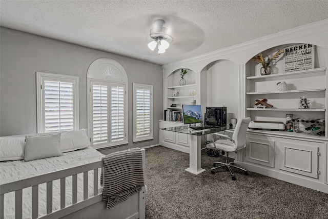 bedroom featuring built in desk, ceiling fan, dark colored carpet, and a textured ceiling