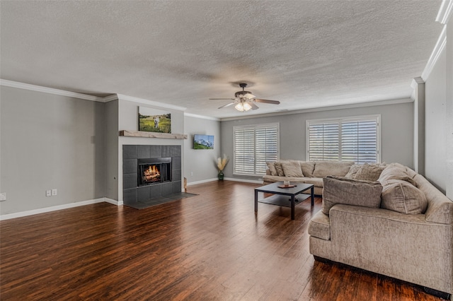 living room with dark hardwood / wood-style floors, a tile fireplace, a textured ceiling, and crown molding