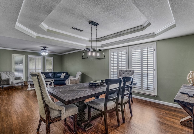 dining room with dark wood-type flooring, a tray ceiling, and ceiling fan