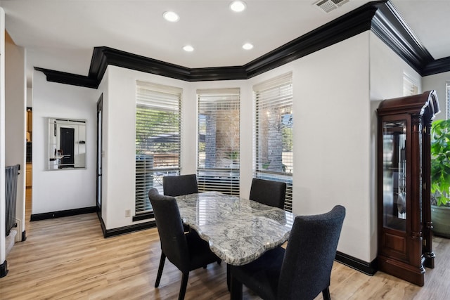 dining room featuring light wood-type flooring and crown molding