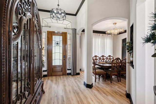 foyer entrance featuring crown molding, a chandelier, and light wood-type flooring