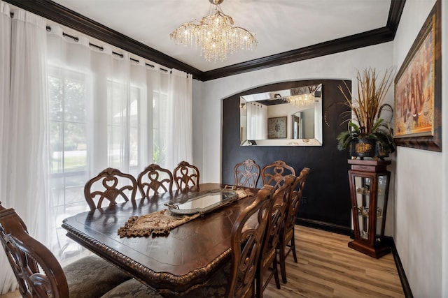 dining area with a wealth of natural light, hardwood / wood-style floors, crown molding, and a notable chandelier