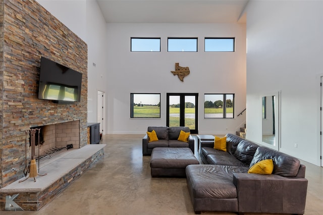 living room featuring concrete floors, a towering ceiling, a wealth of natural light, and a fireplace