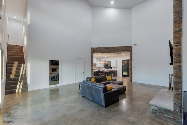 living room with a towering ceiling, a chandelier, and concrete flooring