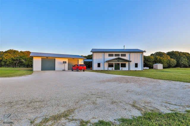 view of front facade with a garage, a front lawn, and an outbuilding