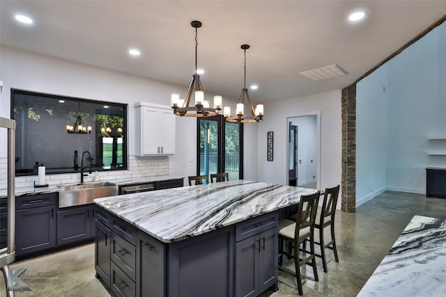 kitchen with decorative backsplash, a kitchen island, sink, pendant lighting, and concrete flooring