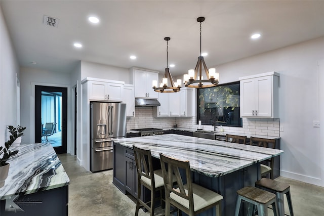 kitchen with a center island, decorative backsplash, stainless steel appliances, and hanging light fixtures