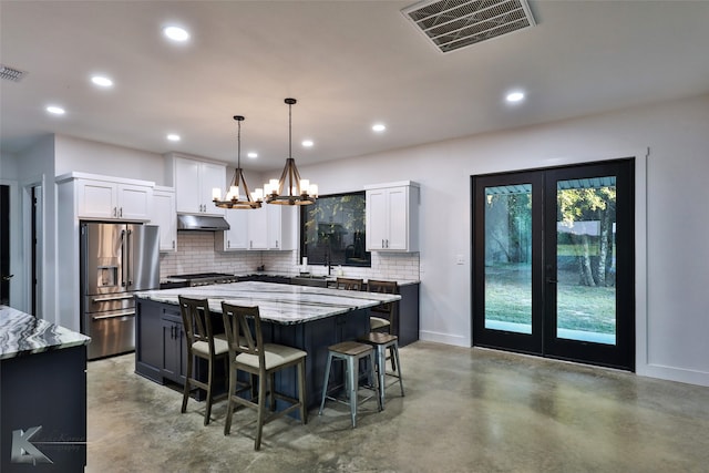 kitchen with light stone countertops, a center island, pendant lighting, high quality fridge, and white cabinets