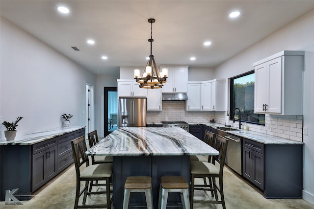 kitchen featuring stainless steel appliances, sink, a center island, decorative light fixtures, and white cabinetry