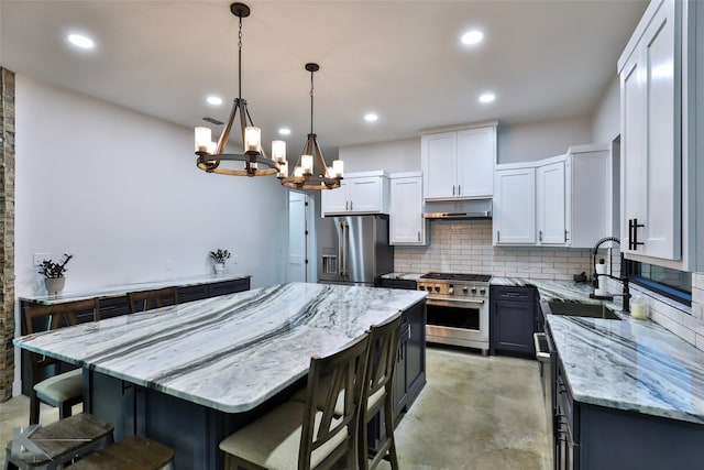 kitchen with premium appliances, sink, a center island, hanging light fixtures, and white cabinetry